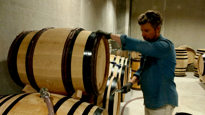 Antoine Lepetit de la Bigne in his cellar with a wine barrel