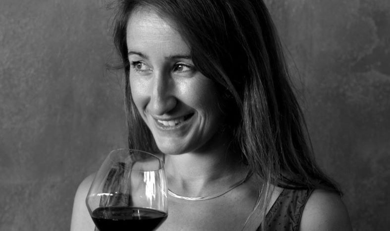 A black and white photo of Laura Aillaud holding a glass of wine