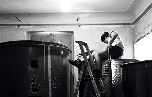Laura Aillaud checking the grapes or wine in the vats in her winery
